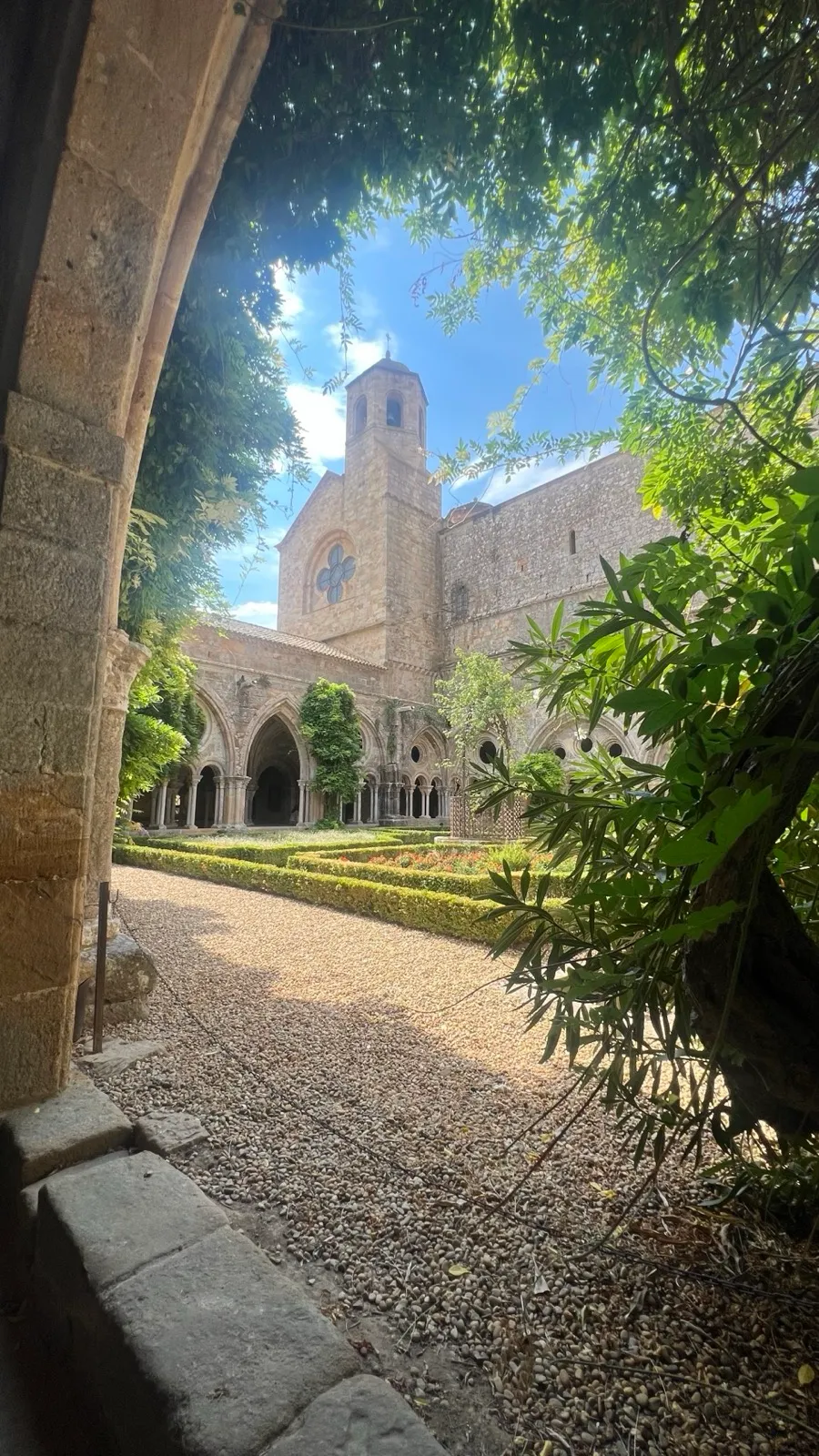 Blick durch einen Steinbogen auf den Kreuzgang und den Glockenturm der Abbaye de Fontfroide