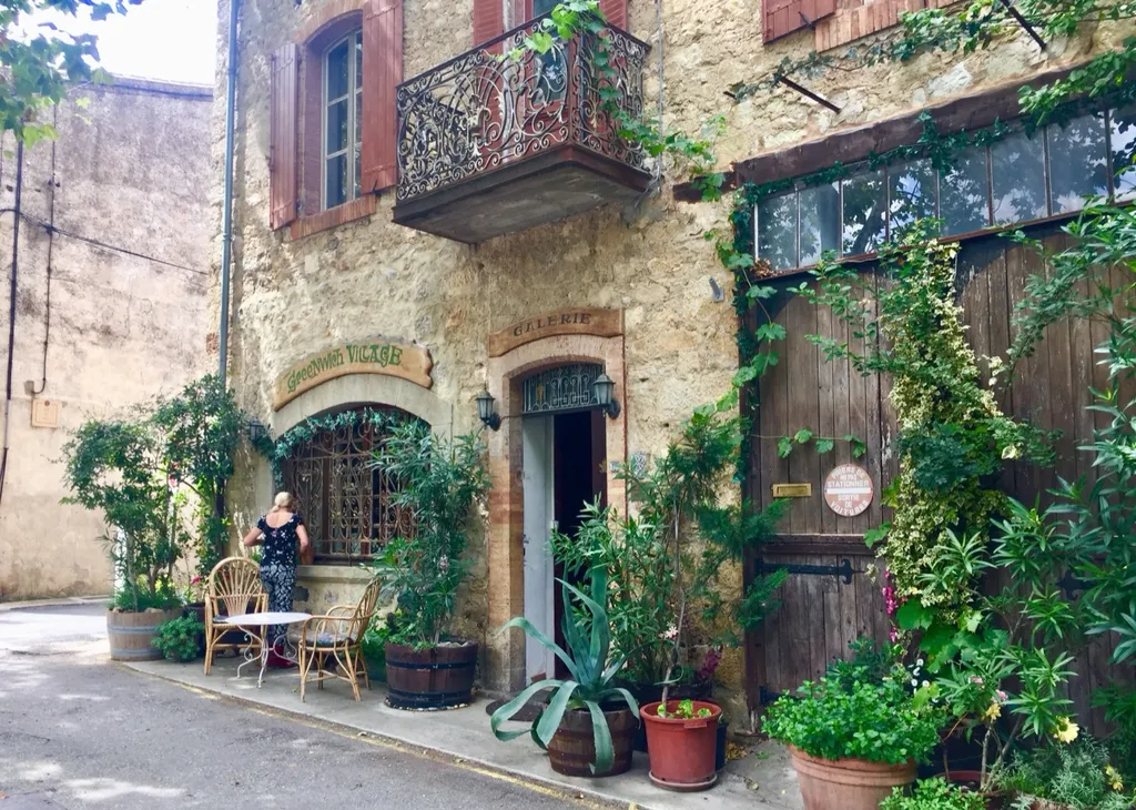 Bewachsene Gasse in Lagrasse mit Galerie, Balkon und Pflanzen vor alten Steinhäusern