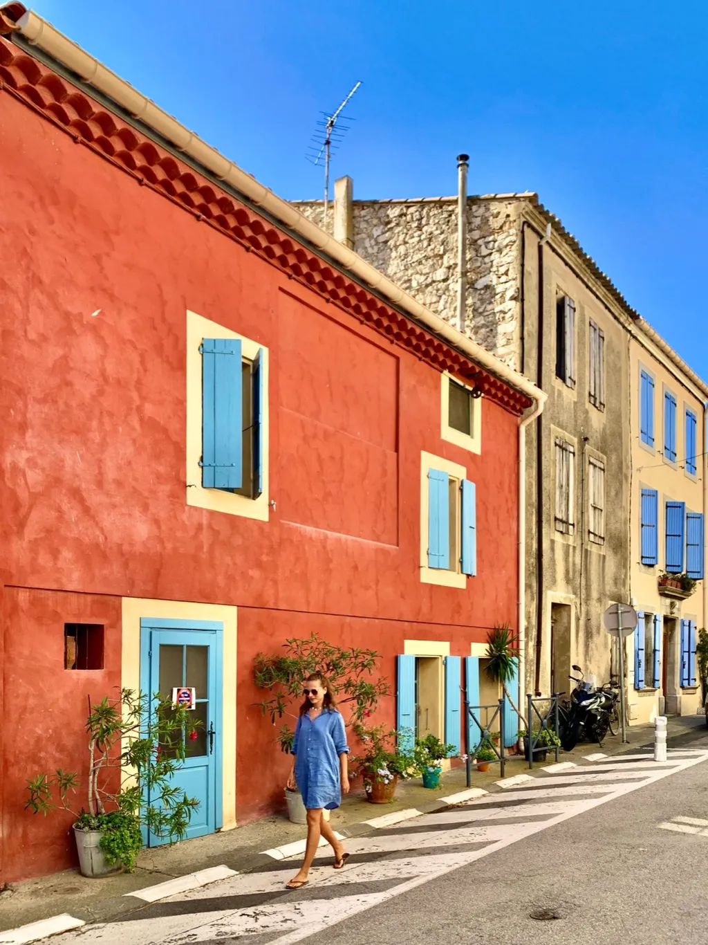 Bunte Häuserzeile in Leucate mit roter Fassade und hellblauen Fensterläden