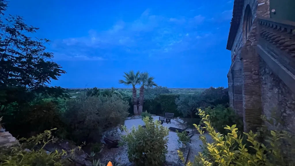 Der Garten der Table de Loréna zur blauen Stunde mit Palmen und Blick über die Ebene