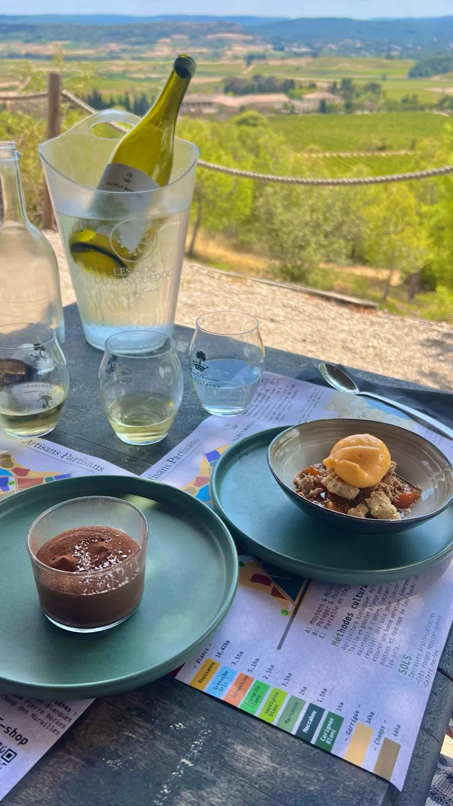Dessert und Weißwein auf der Terrasse des Château Ollieux Romanis mit Blick über die Reben