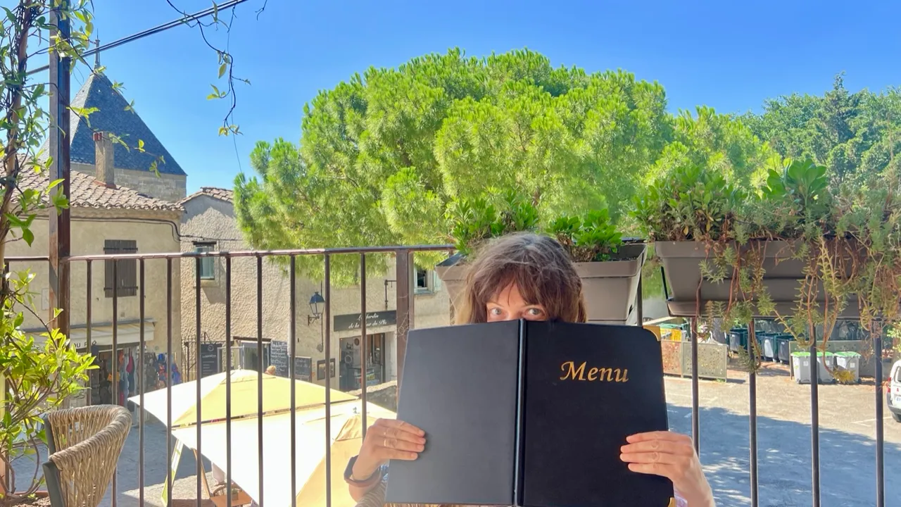 Caroline studiert die Menükarte auf einer Restaurant-Terrasse in Carcassonne