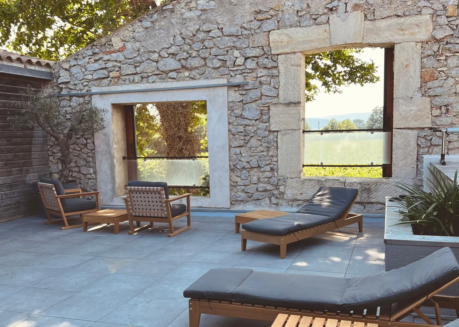 Weitläufige Dachterrasse mit Lounge-Möbeln und historischer Steinmauer