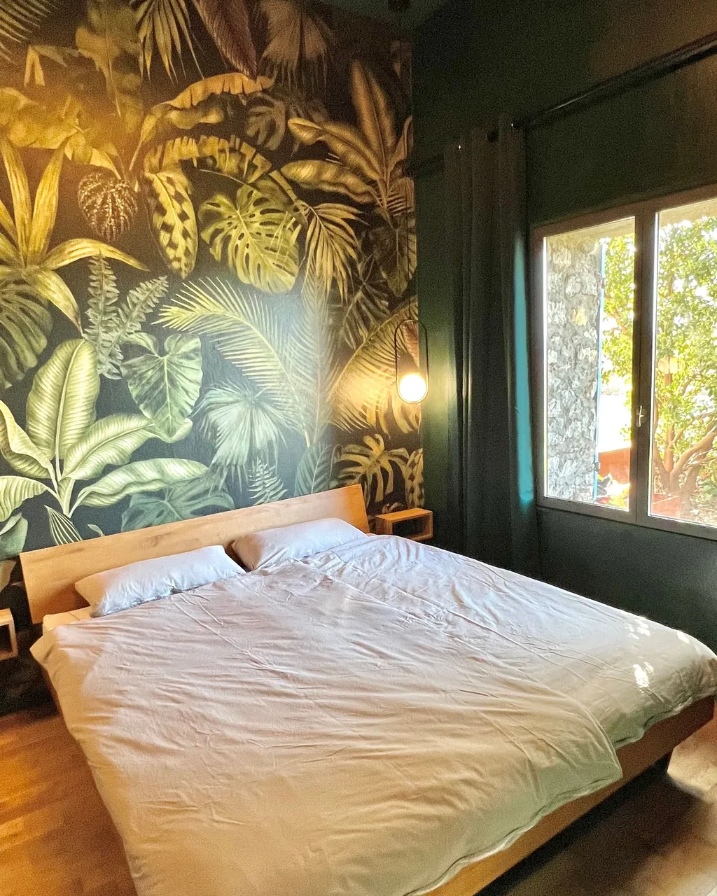 Schlafzimmer des Studios mit Dschungel-Tapete und Blick in den Garten