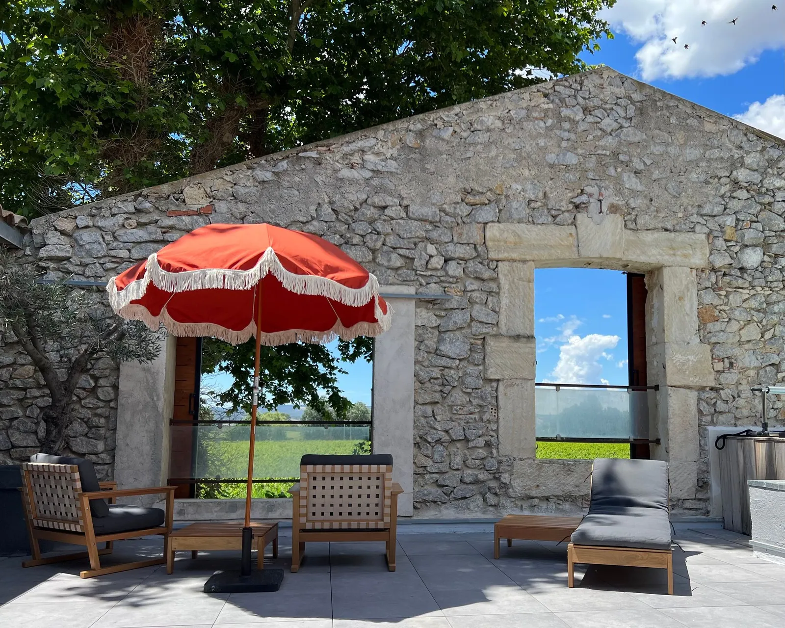 Dachterrasse des Penthouse mit rotem Sonnenschirm und Blick auf die Weinberge