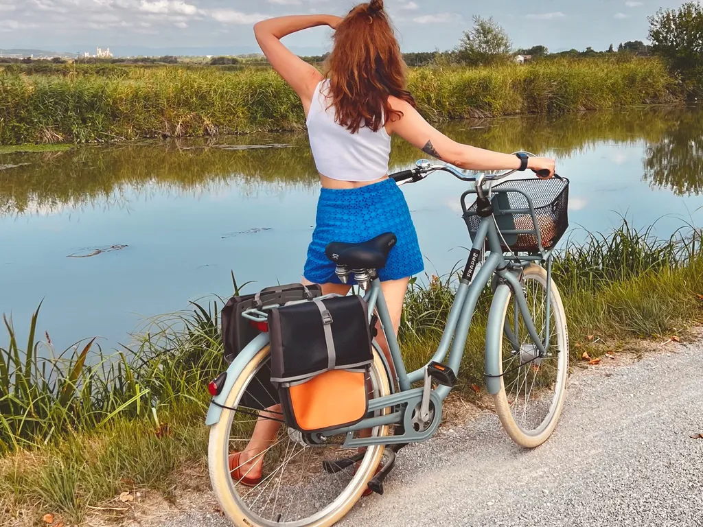Citybike mit Packtaschen am Ufer des Canal de la Robine, im Hintergrund die Kathedrale von Narbonne