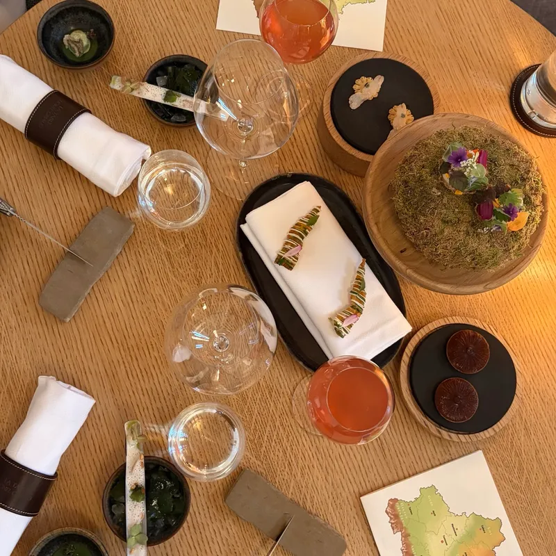 Der Tisch der Table Lionel Giraud von oben, voller kleiner Amuse-bouches auf Holz, Stein und Moos
