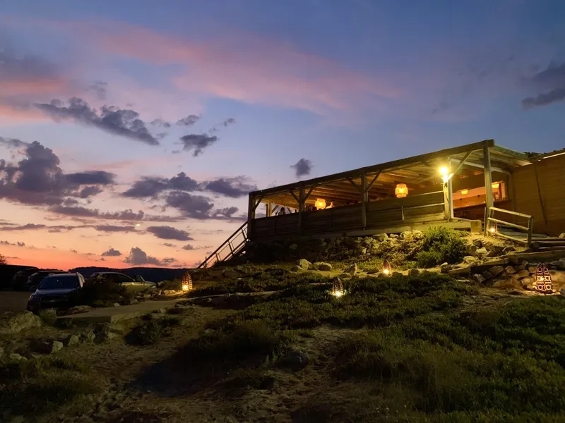 Die beleuchtete Holzterrasse des Mamamouchi in der Abenddämmerung