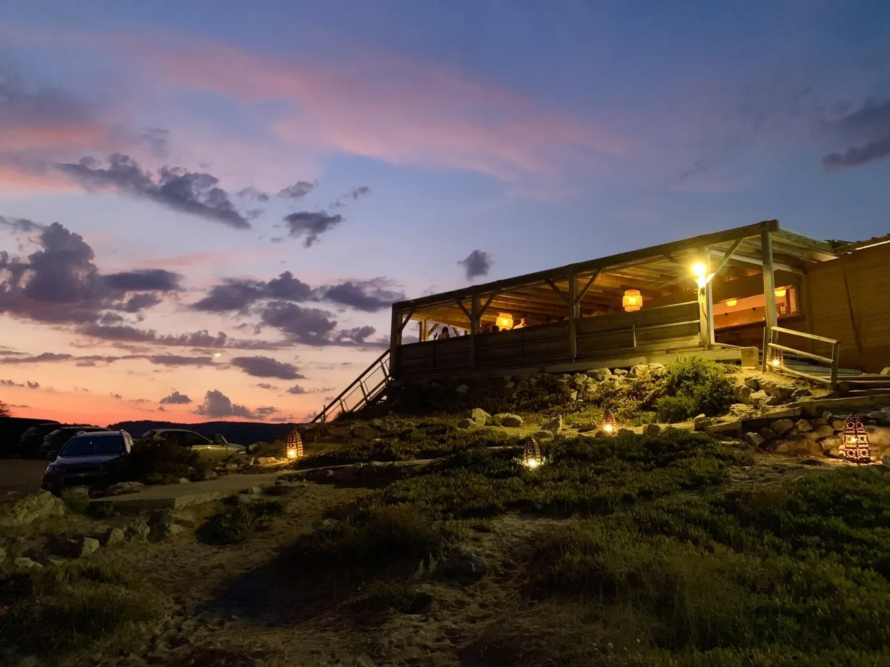 Die beleuchtete Holzterrasse des Mamamouchi in der Abenddämmerung