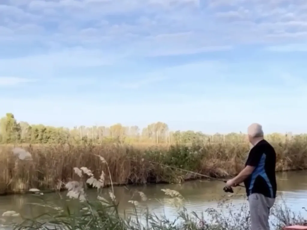 Ein Angler wirft am schilfbewachsenen Ufer des Canal de la Robine aus
