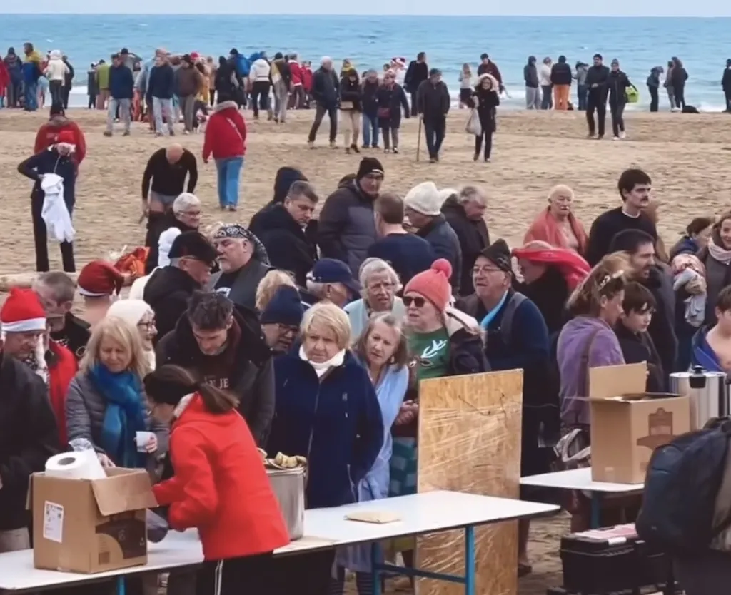 Der Strand von Gruissan am 1. Januar: Zuschauer in Winterjacken, Weihnachtsmützen und ein Tisch mit Glühwein