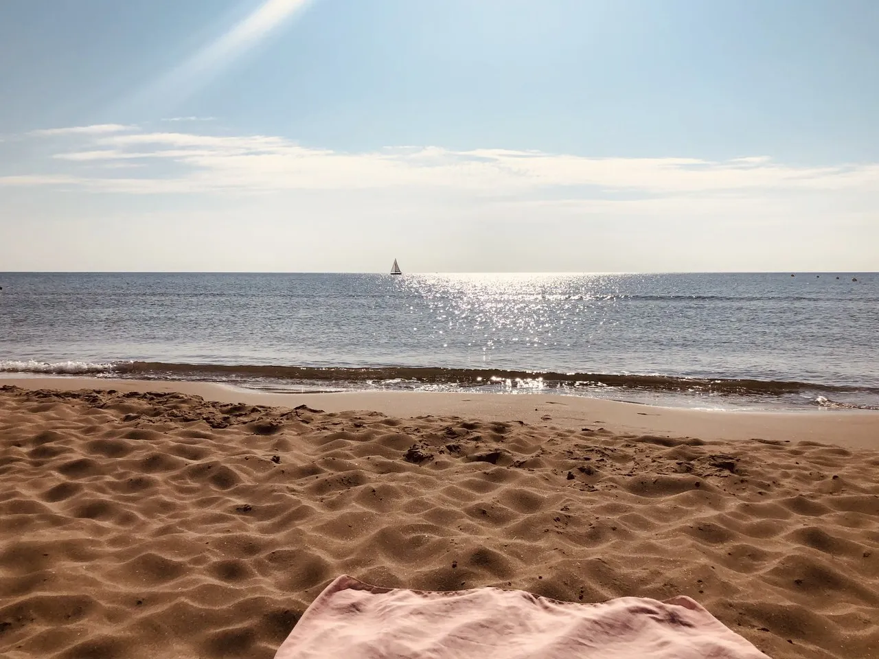 Ein Segelboot am Horizont vor Narbonne-Plage, die Sonne glitzert auf dem Wasser